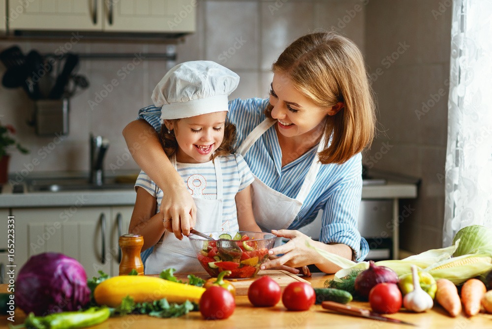 健康饮食。家庭母亲和小女孩在家厨房准备素食沙拉