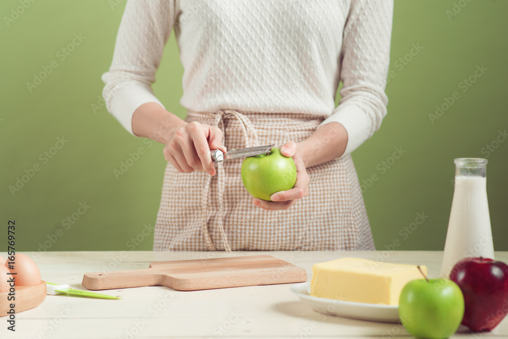 穿着围裙的家庭主妇制作。烹饪苹果蛋糕的步骤。切青苹果。