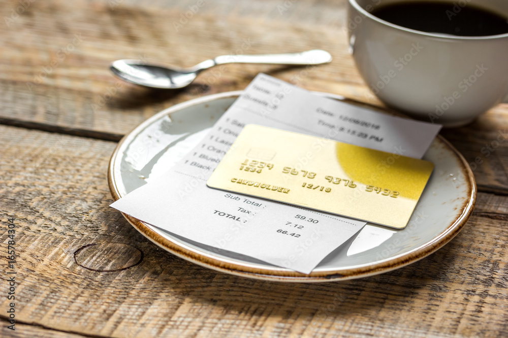 木桌背景上的餐厅账单、卡片和咖啡