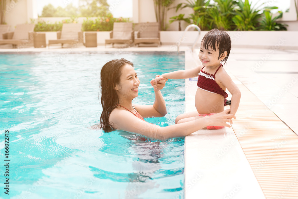 母亲和女婴在游泳池里玩得很开心。暑假和度假概念