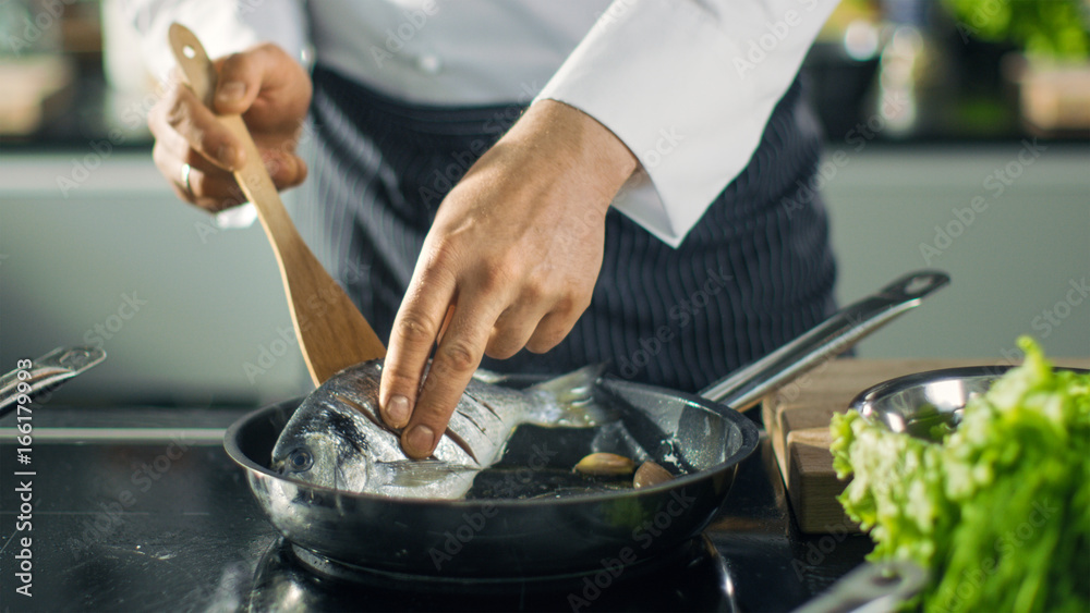 著名餐厅厨师在热锅上翻鱼。锅里蔬菜的特写镜头