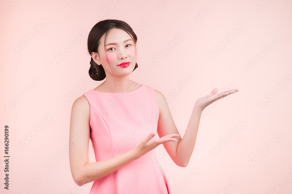 可爱的亚洲年轻女子，带着时尚的妆容，手在粉色上露出孤立的东西。
