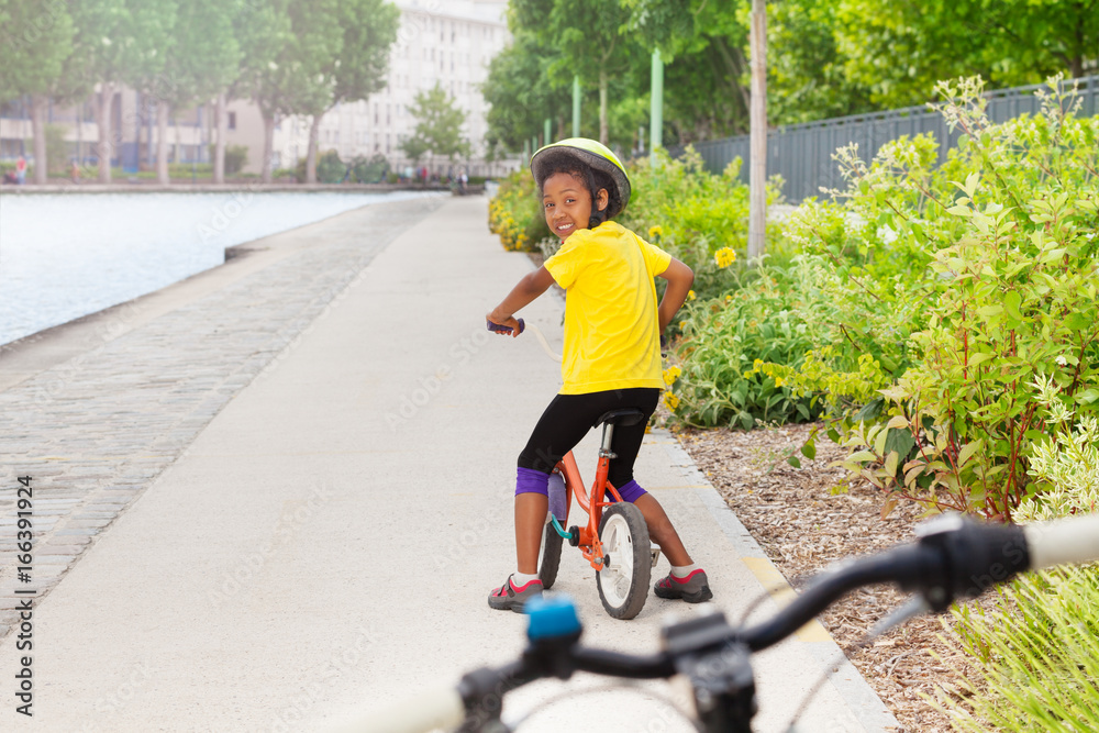 城市自行车道上骑自行车的非洲女孩