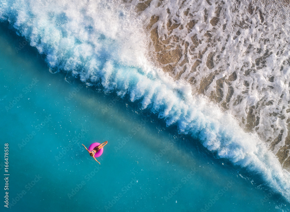 奥卢登透明的绿松石海中，一名年轻女子在粉色游泳圈上游泳的鸟瞰图