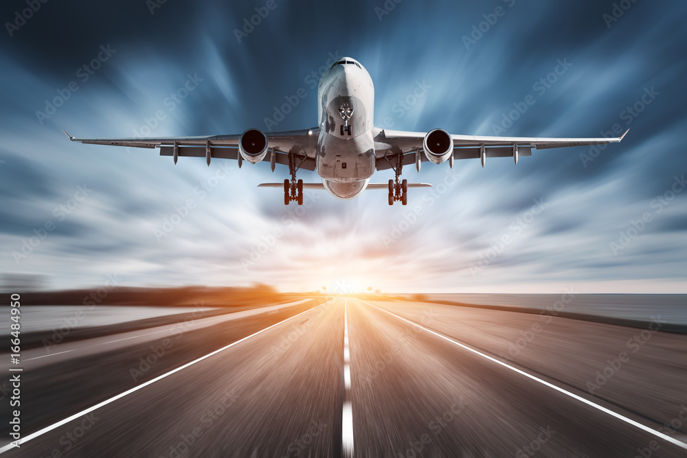 Airplane and road with motion blur effect at sunset. Landscape with passenger airplane is flying ove