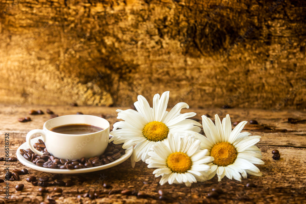 木桌上的咖啡杯和油炸咖啡豆，木桌上开着漂亮的白花