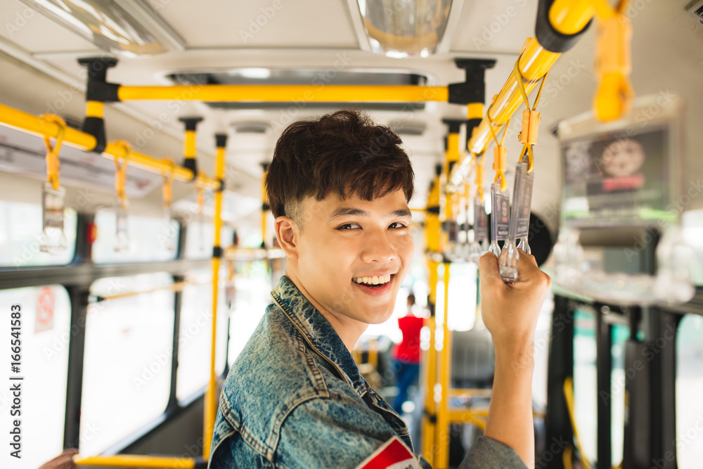 亚洲男子乘坐公共交通工具，站在公交车内。