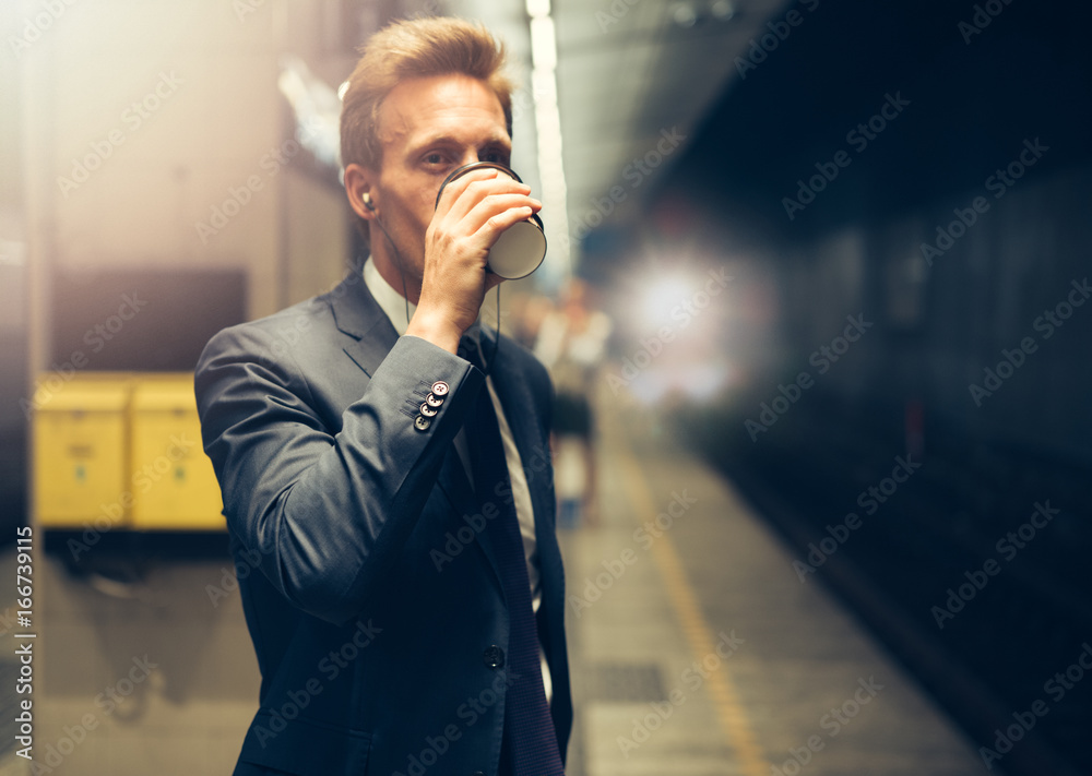 商人在等地铁时喝咖啡