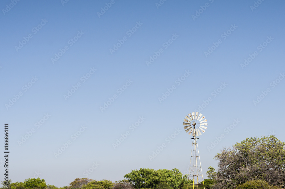 Pinwheel / Windmill over tree tops, alternative energy generation by wind energy.