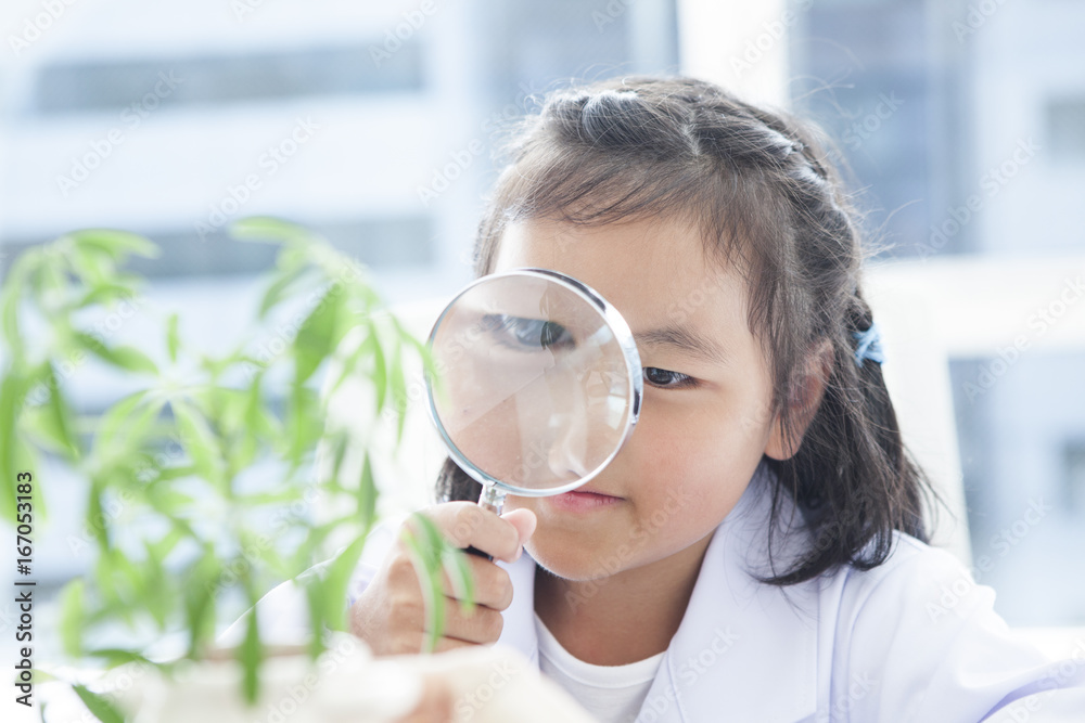 一个穿着白色西装的女孩用放大镜观看植物