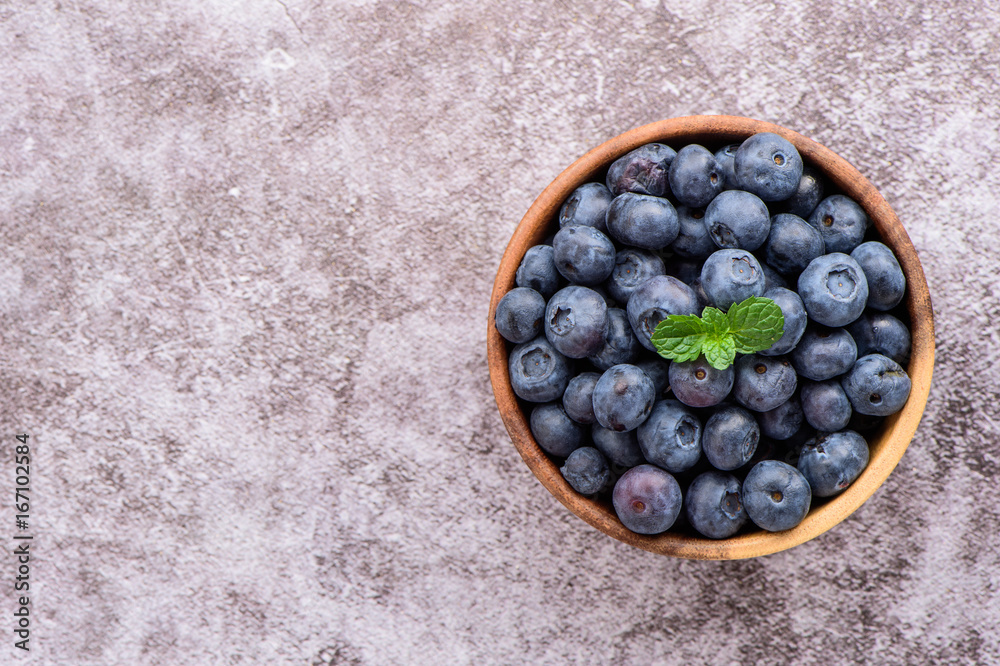 蓝莓和香草薄荷放在石头背景的木碗里，俯视图