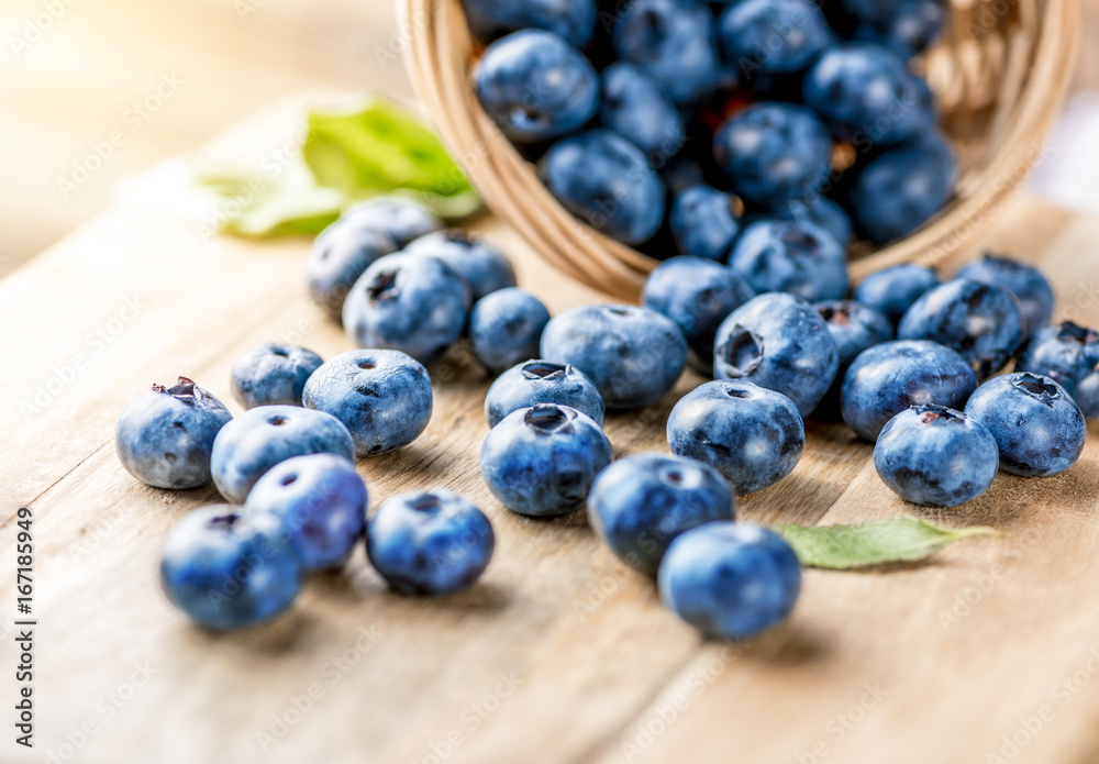 新鲜的蓝莓放在木制乡村木桌上。多汁新鲜的蓝莓带绿叶。Bi