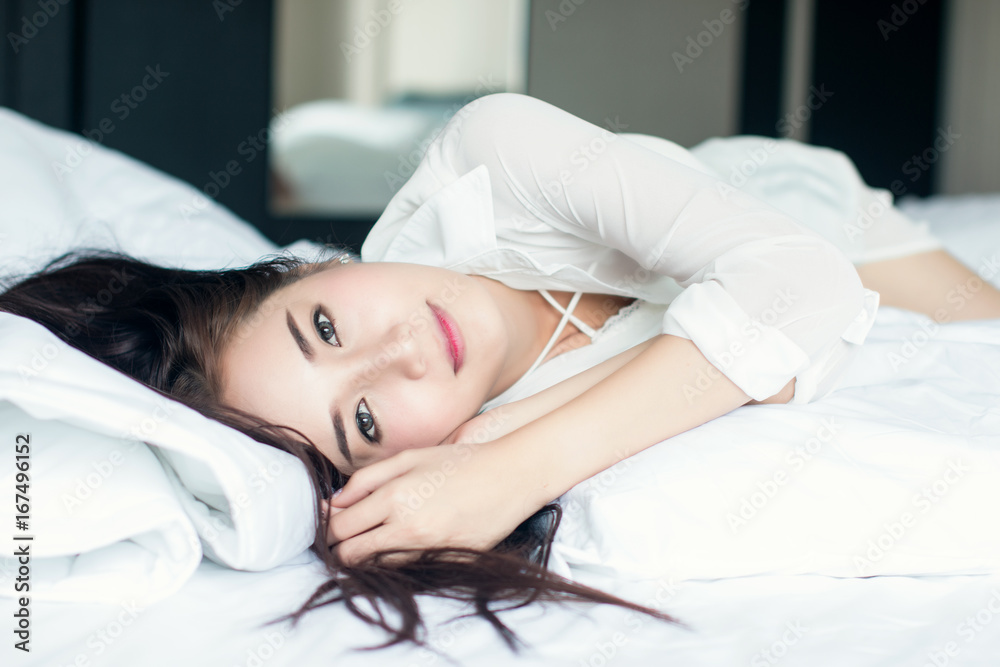 漂亮女孩穿着白色连衣裙，睡在卧室里。