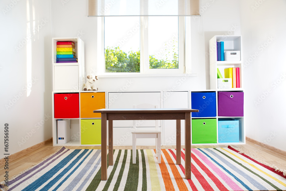 彩色儿童房，白色墙壁和家具。家里有彩虹地毯，有风