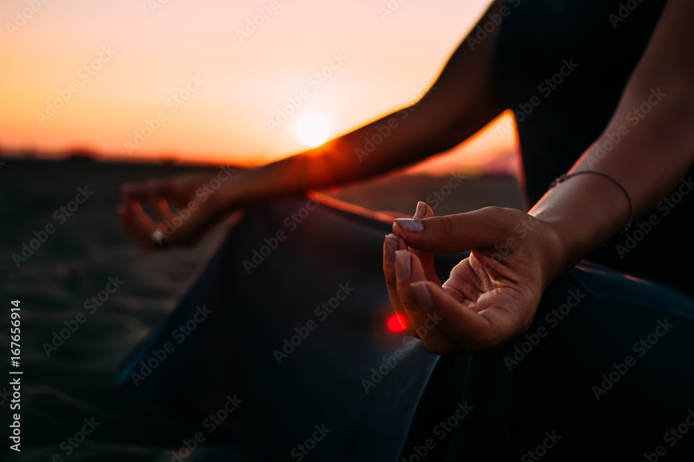 日落时，一位女士在海滩上做瑜伽的特写。微光照片。
