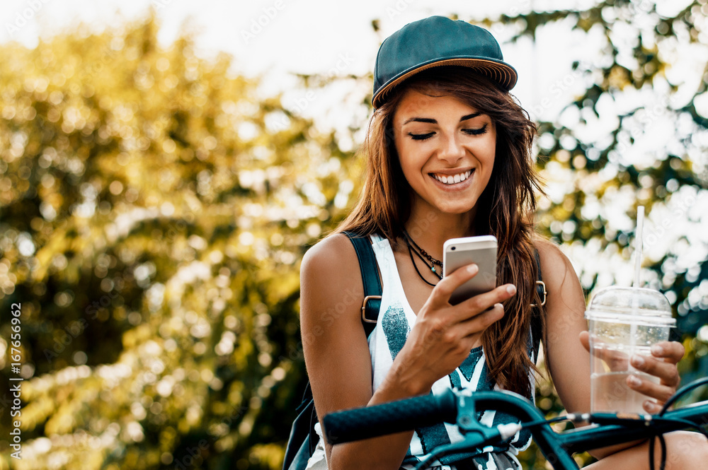 城市生活方式时尚时尚女孩骑自行车使用智能手机