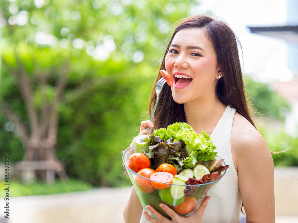 年轻漂亮的亚洲女人吃新鲜干净的食物，配番茄蔬菜和水果，有益健康