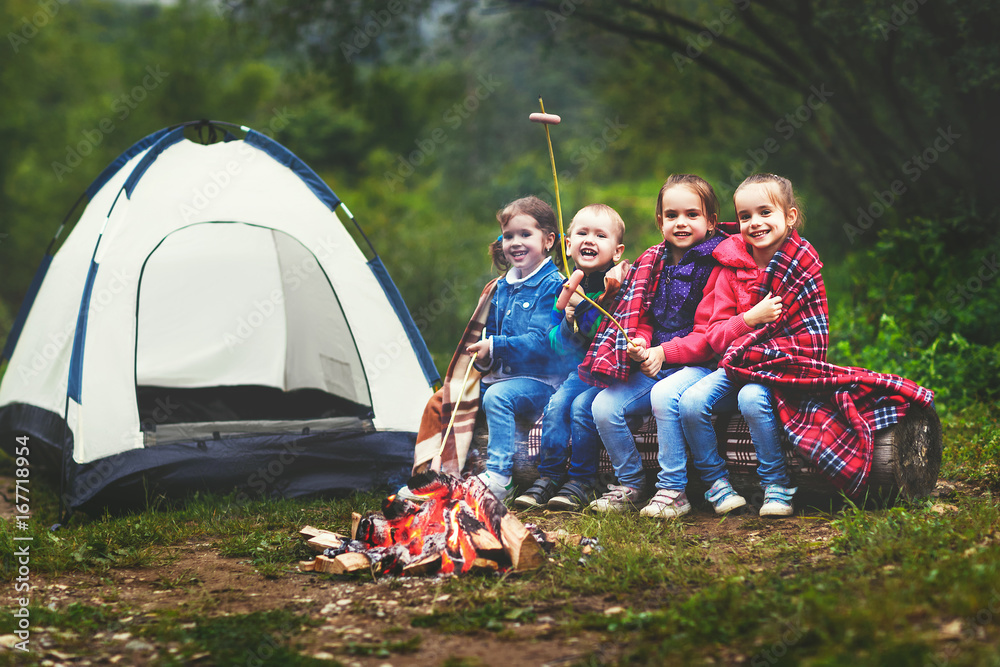 孩子们在帐篷附近的木桩上笑着炸香肠