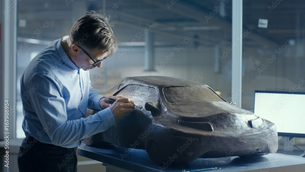 灰色头发的汽车设计师用可塑粘土和金属丝雕刻出未来主义的汽车模型。He-Wor