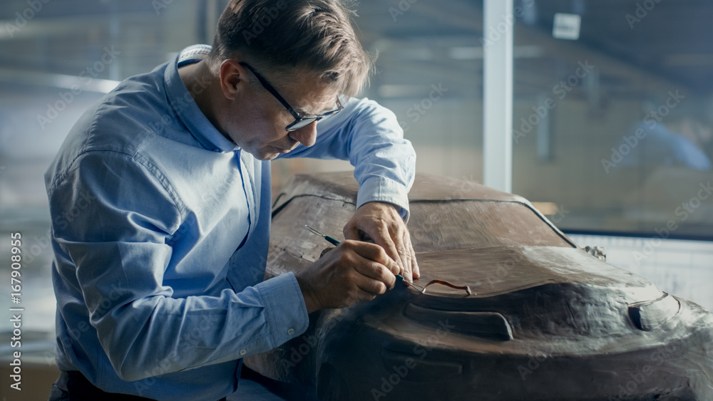Rake高级汽车设计师用塑性粘土雕刻未来主义汽车模型。他在