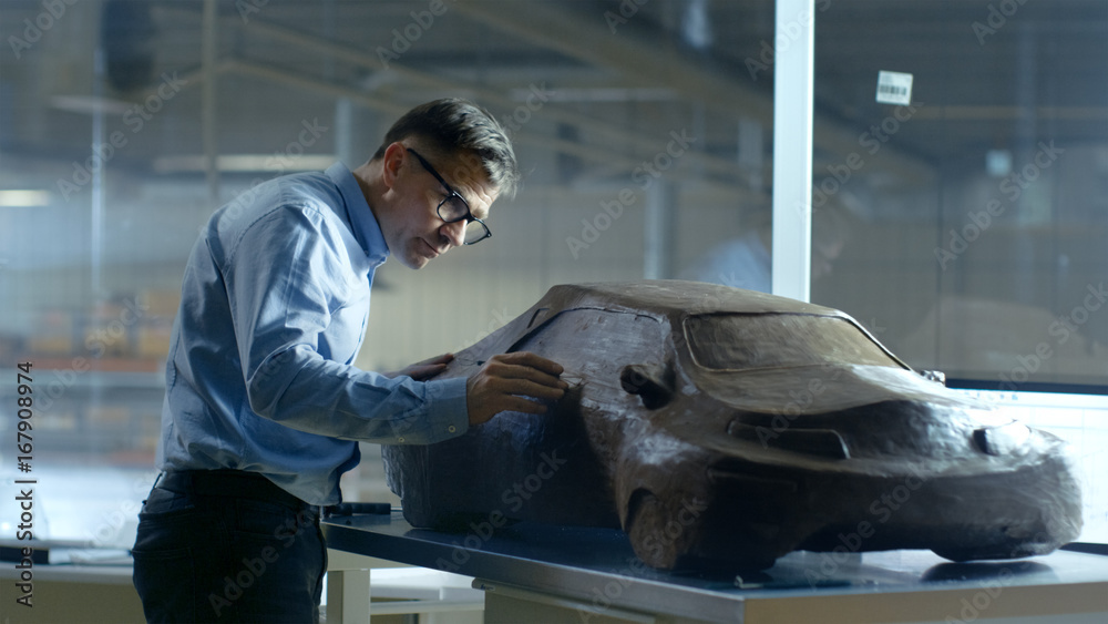 Chief Automotive Designer with Rake Sculpts Futuristic  Car Model from Plasticine Clay. He Works in 