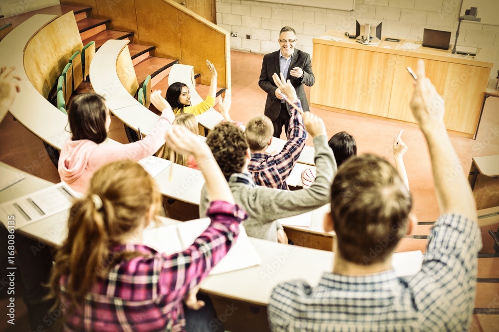 Students raising hands with teacher in lecture hall