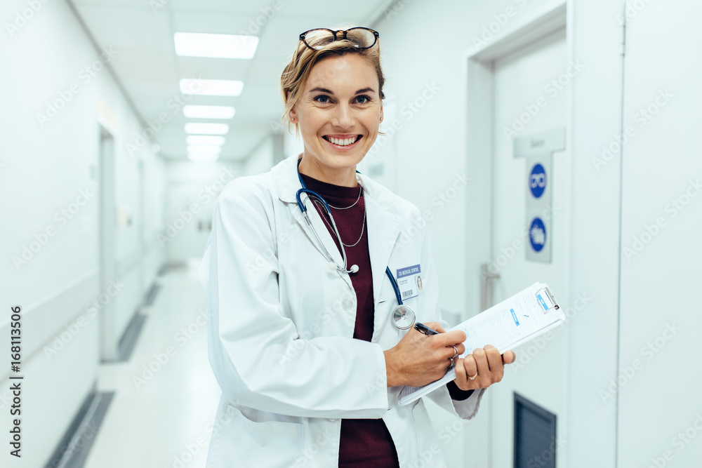 快乐的年轻女医生站在医院走廊