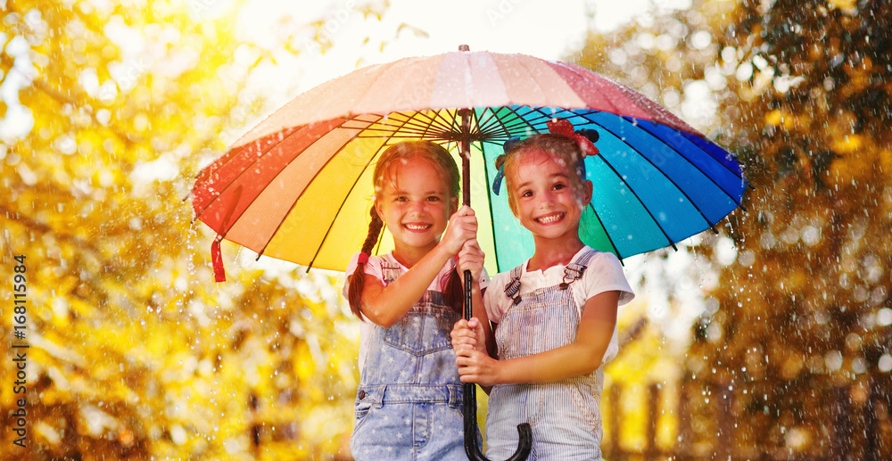 快乐有趣的姐妹双胞胎秋天带伞的小女孩