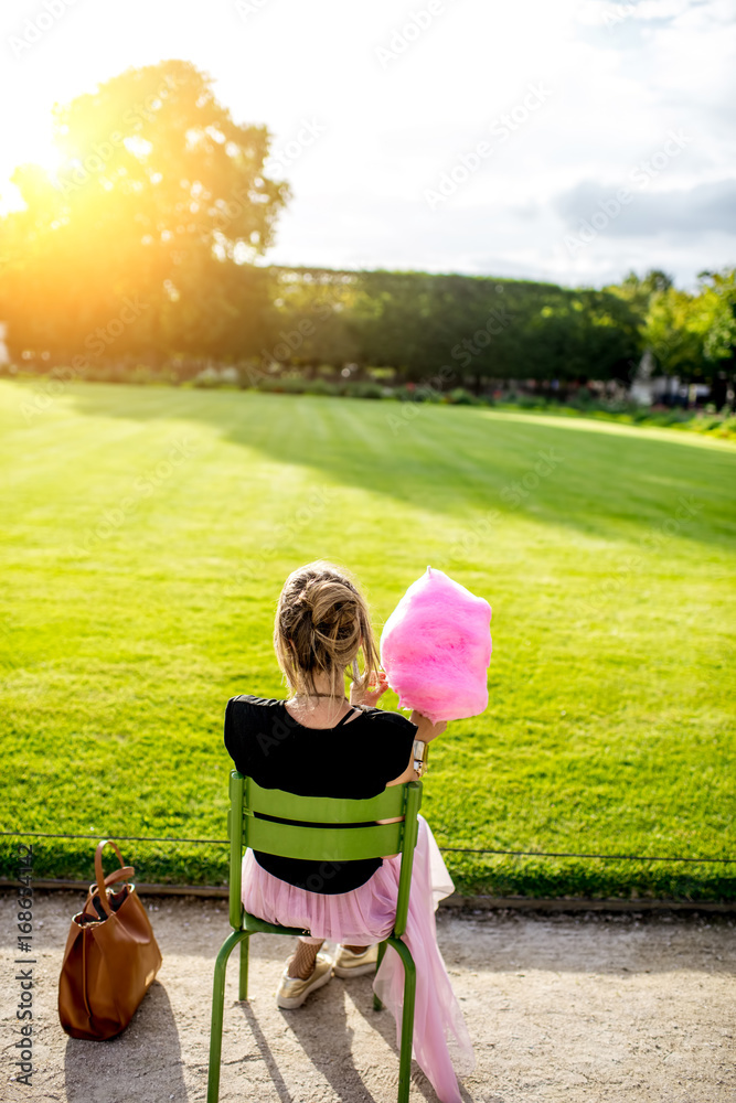 拿着粉色棉花糖的年轻女子坐在公园的户外