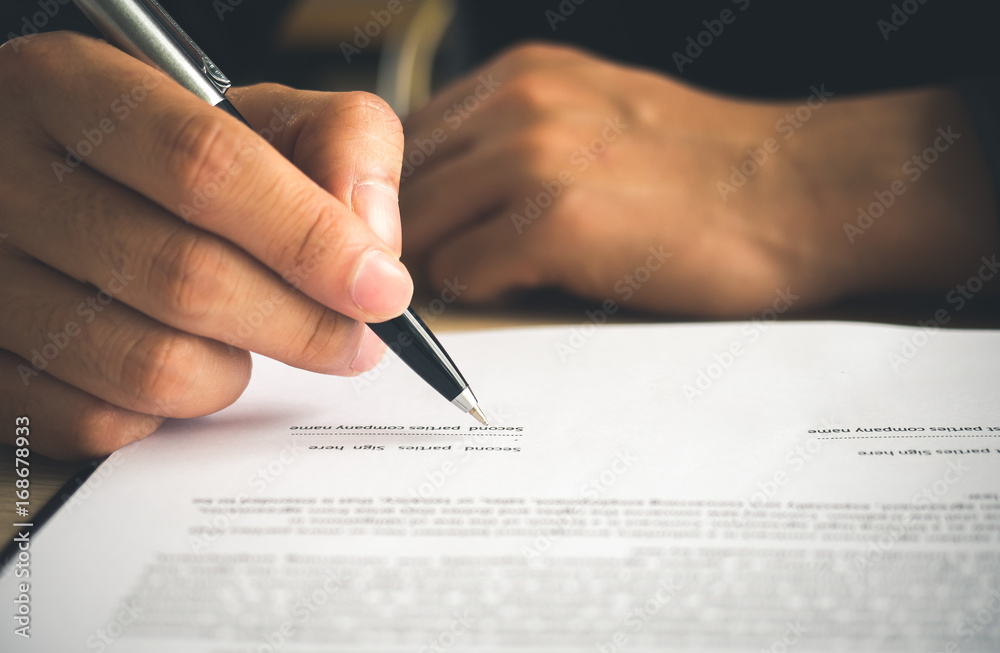 商人的手在合同/书籍/笔记本上书写，签署商业协议。