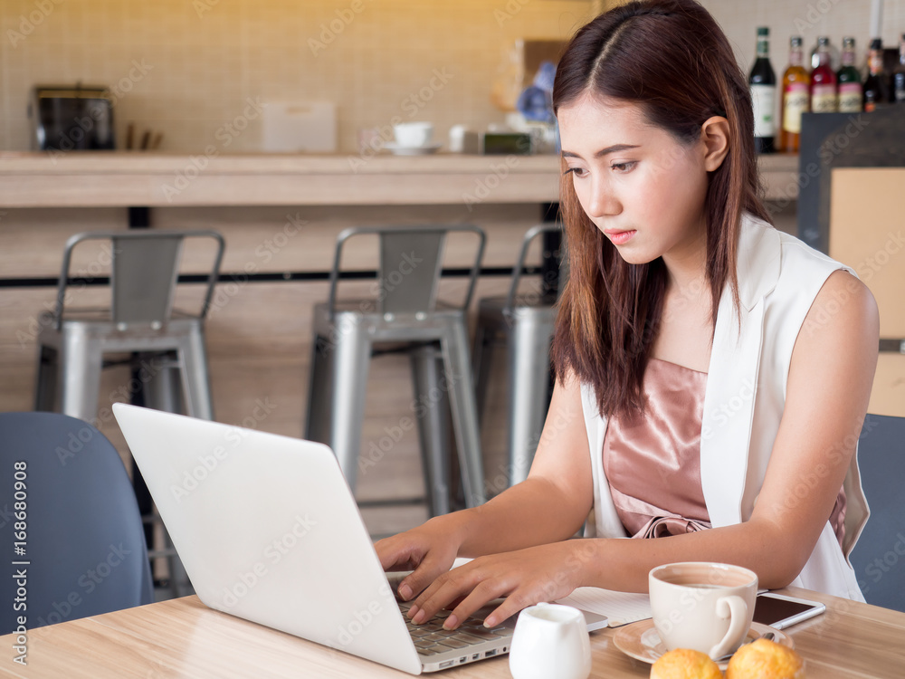年轻的亚洲女商人，工作，用笔记本电脑写电子邮件，喝咖啡，网上购物