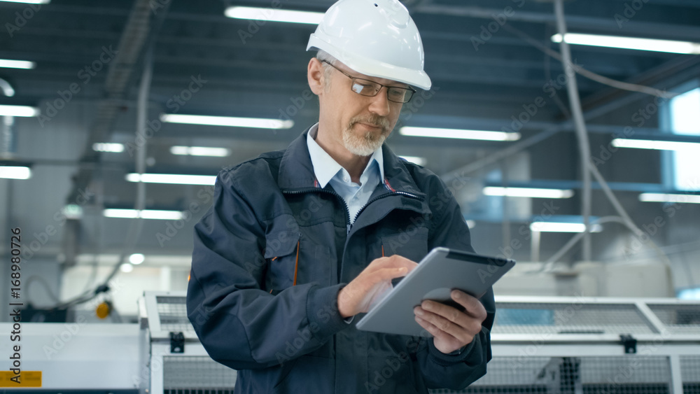 安全帽公司的高级工程师正在工厂里使用平板电脑。