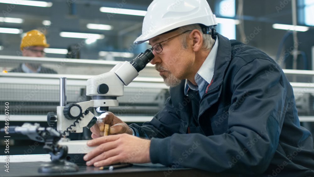 高级工程师正在工厂的显微镜下检查一个细节。