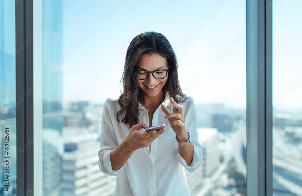 快乐的女商人在办公室用手机。
