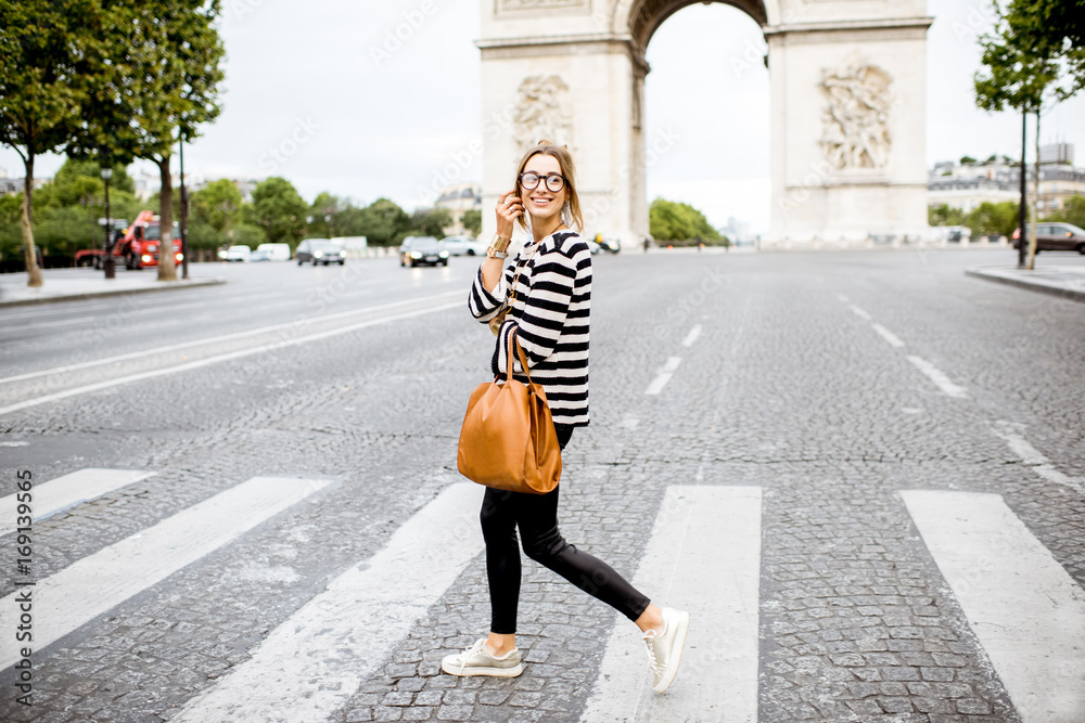 身穿条纹毛衣的年轻商务女性穿过巴黎著名凯旋门附近的街道