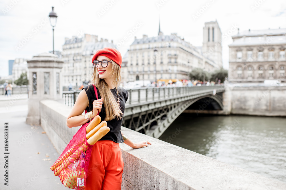 巴黎街头，一位年轻时尚的红帽子女士提着装满法国食物的网袋行走