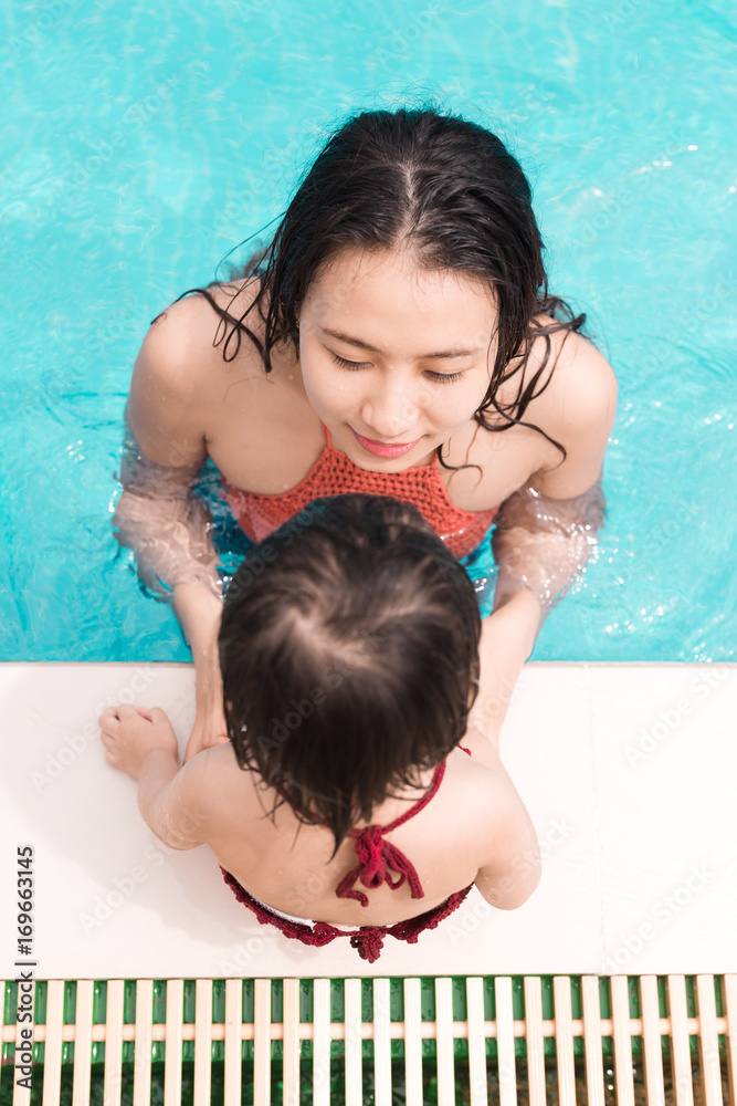 母亲和女儿在游泳池里玩得很开心。暑假和度假概念