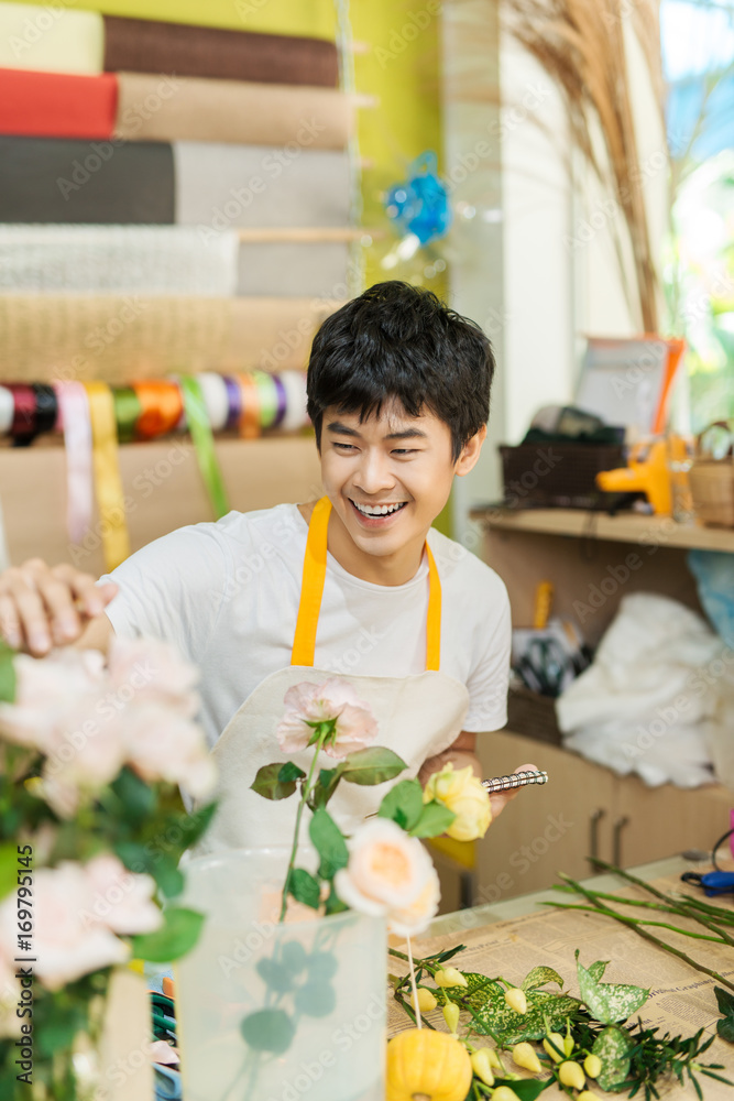 微笑的年轻亚洲花店男子在花店制作花束