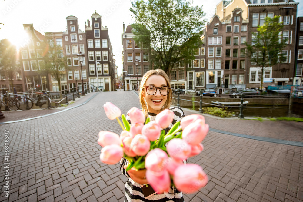 Amstredam，一位年轻快乐的女士手持一束粉色郁金香站在户外的肖像