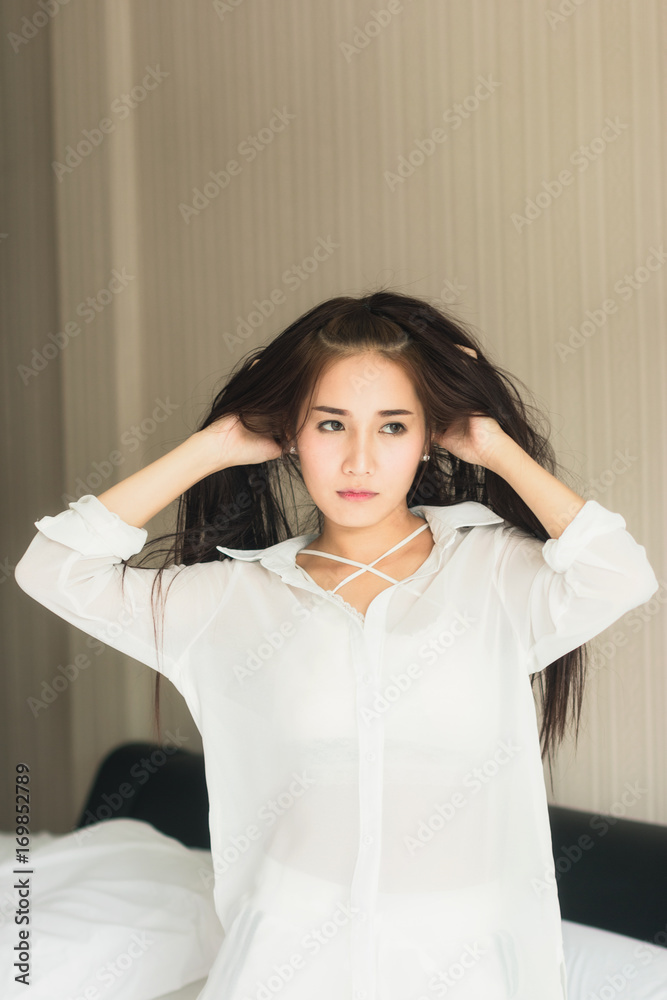 漂亮的亚洲女人穿着白色连衣裙，看起来很好看。在卧室里放松。