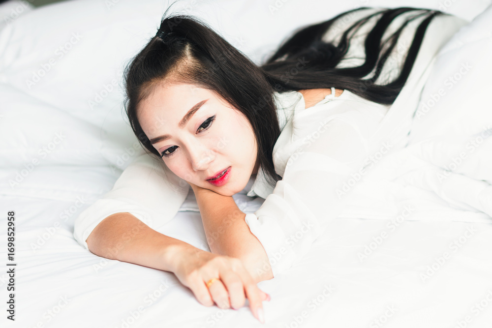 一个漂亮的亚洲女孩穿着白色连衣裙，在卧室里休息。