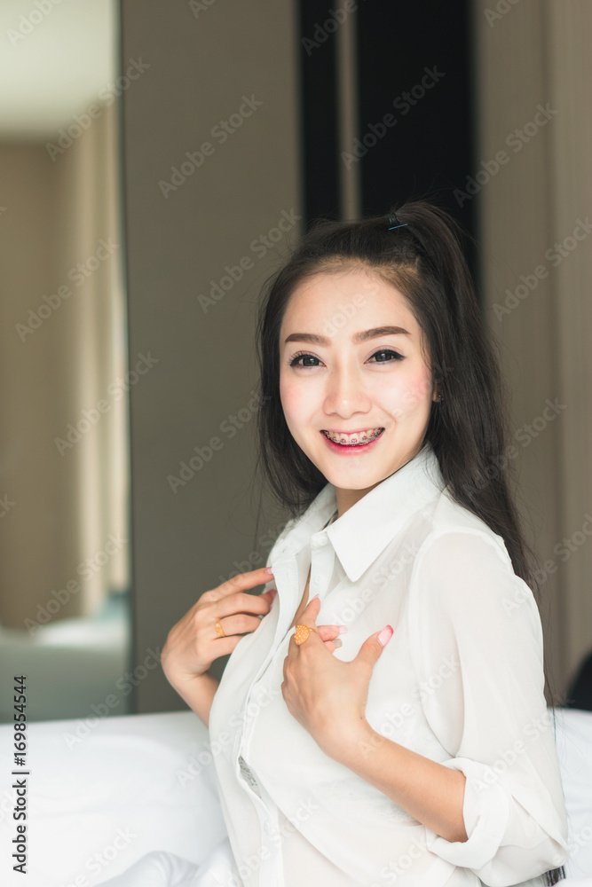 漂亮的亚洲女人穿着白色连衣裙，看起来很好看。在卧室里放松。