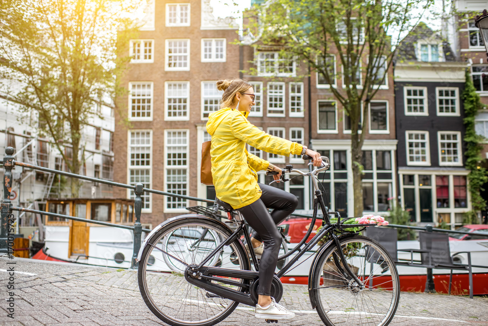 阿姆斯特丹市一名身穿黄色雨衣、挎包带花的年轻女子骑自行车