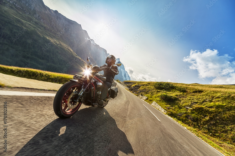 摩托车司机在阿尔卑斯山高速公路上骑行。户外摄影