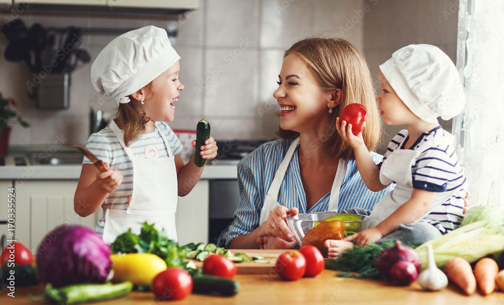 健康饮食。幸福的家庭母亲和孩子们在厨房准备蔬菜沙拉。