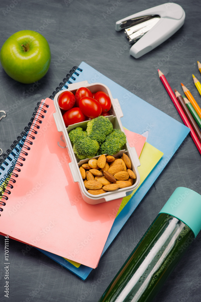 School breakfast on desk with books and pen on board background