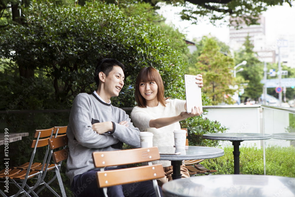 一对年轻夫妇试图在咖啡馆露台上拍照
