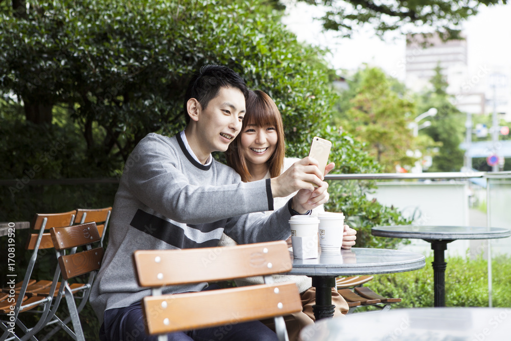 一对年轻夫妇试图在咖啡馆露台上拍照
