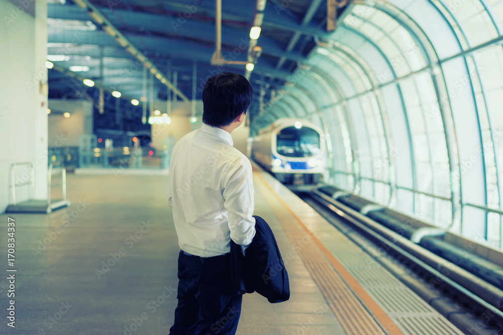 亚洲年轻商人在火车站等地铁。商务旅行理念。