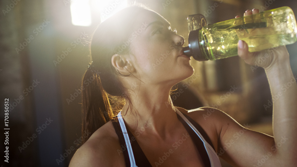 强壮的运动女性在交叉健身健美训练中筋疲力尽后用水瓶喝水